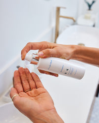 Fresh Start Duo hand dispensing cleanser with silver pump above open palm in gallery position 1 bathroom setting