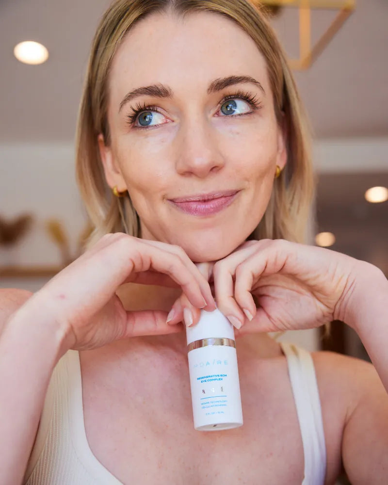 Smiling woman holding Regenerative ECM Eye Complex bottle in gallery p