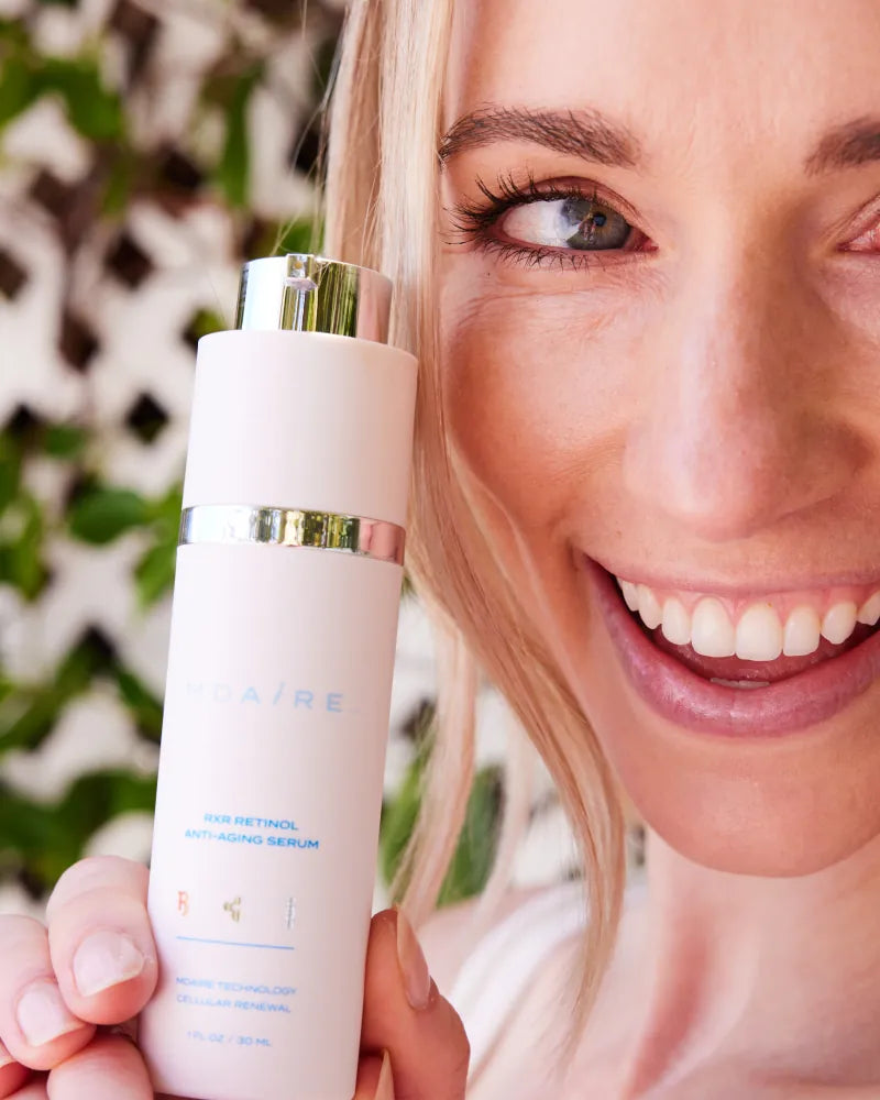 Smiling woman showcasing RXR Retinol Anti-Aging Serum by Dr. Stefani K