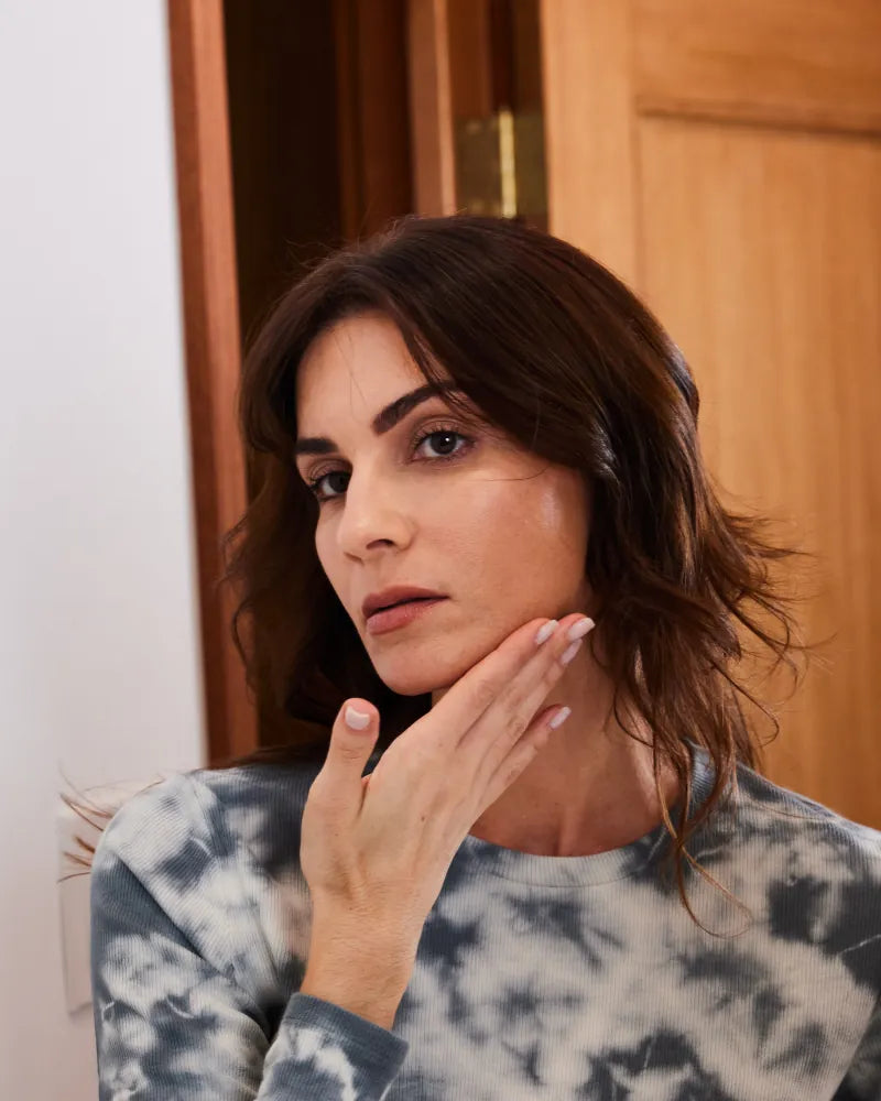 Woman gently touching her cheek demonstrating skincare with Vitamin C-